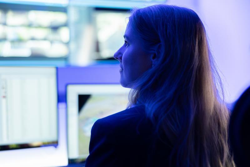 Workrate vrouwelijke beveiliger kijkt rechts in controlekamer met monitoren