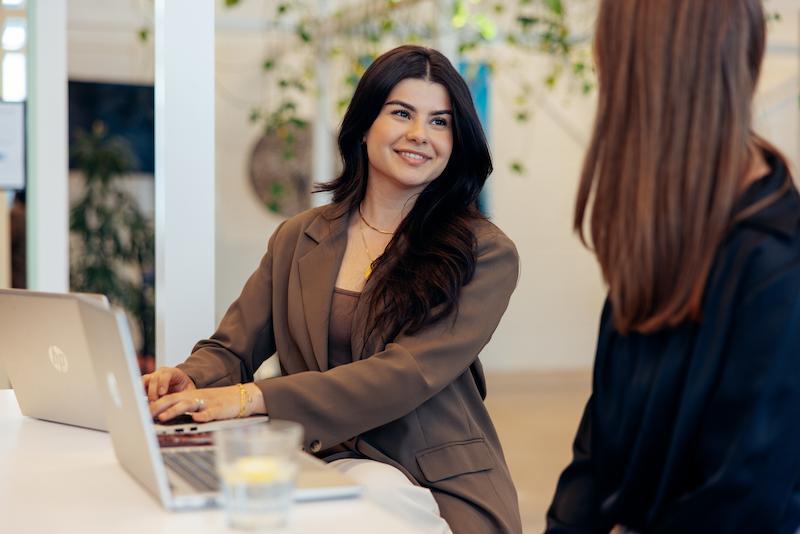 Women in brown suit smiling towards her collegae